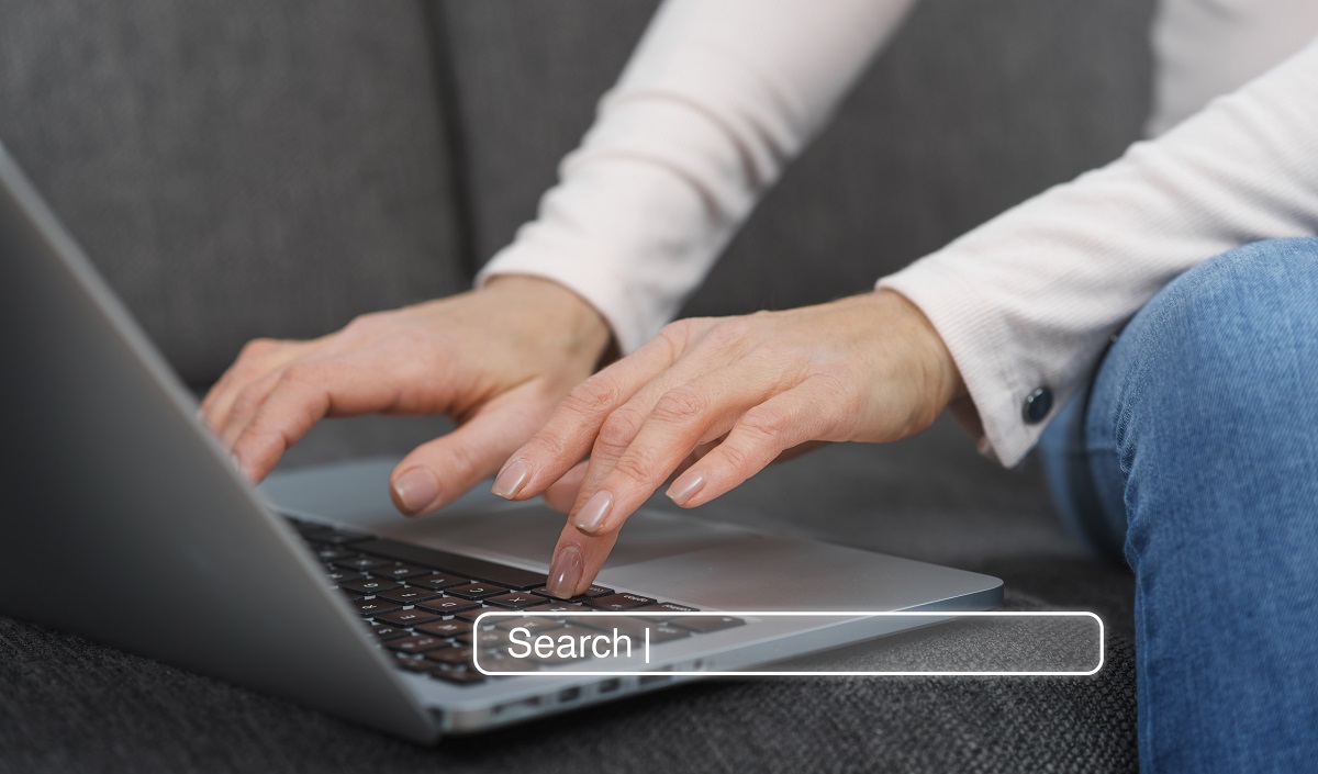 man typing on a laptop, with a graphic search bar